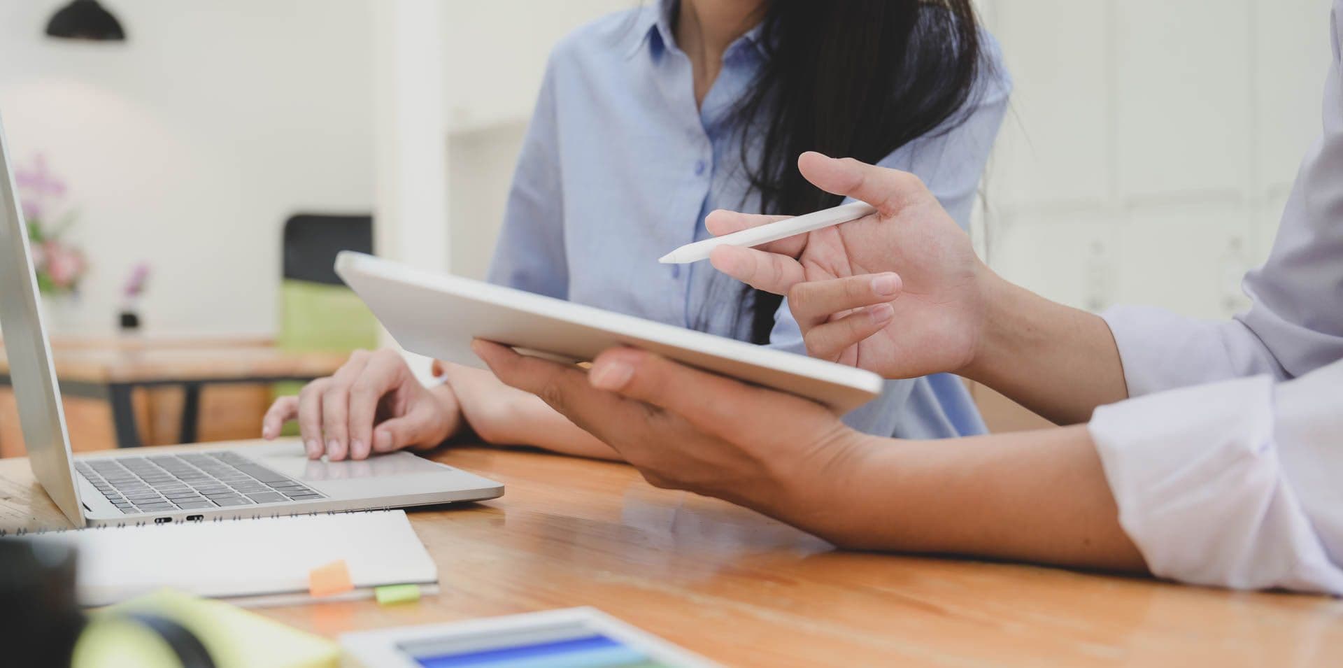 Personen an Tablet und Laptop, die sich was erklären